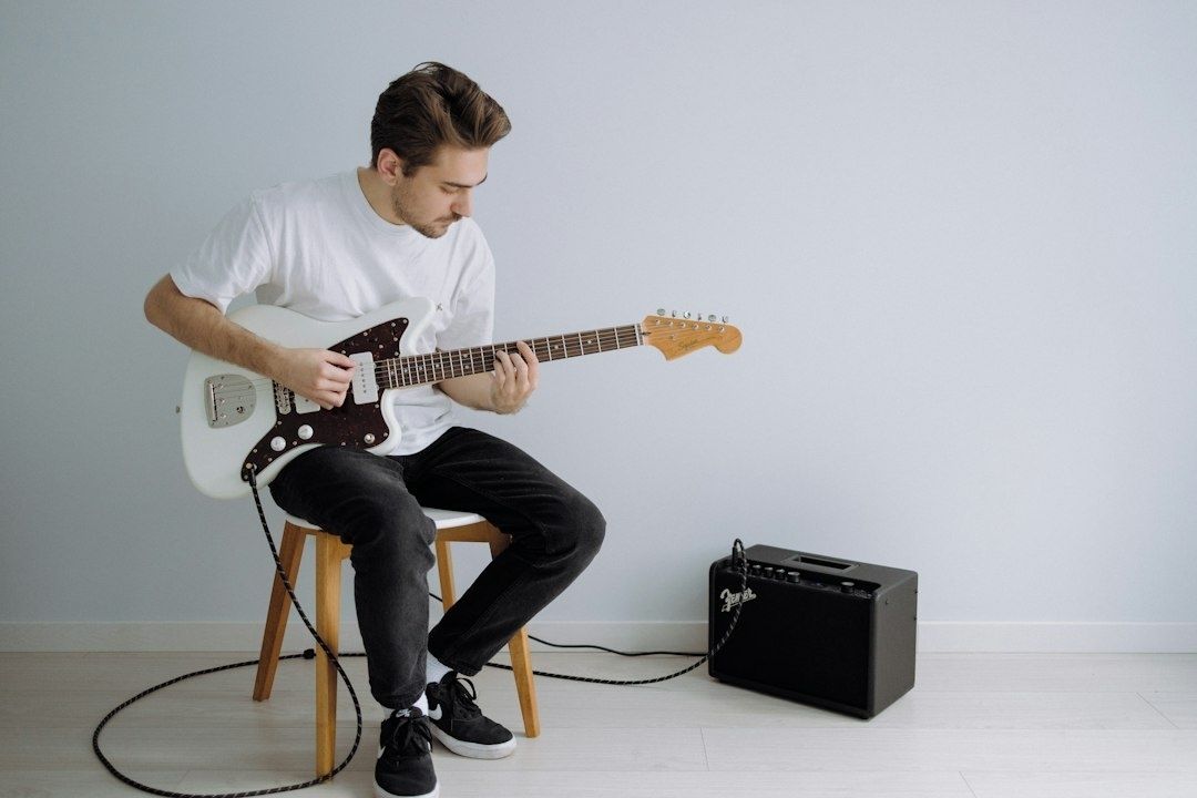 Musician playing an electric guitar connected to a Fender amplifier